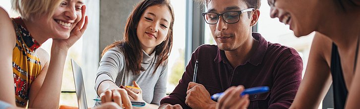 Vier junge Menschen, die gemeinsam etwas erarbeiten