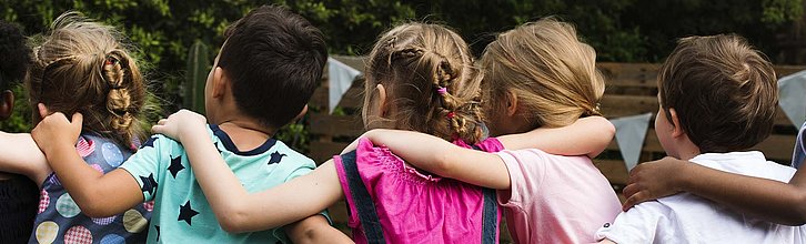 Eine Reihe von Kindern, die die Arme umeinander legen.